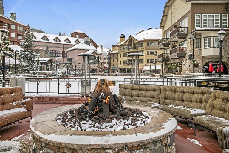 A snowy outdoor view of Beaver Creak St James, with a fire pit surrounded by sofas