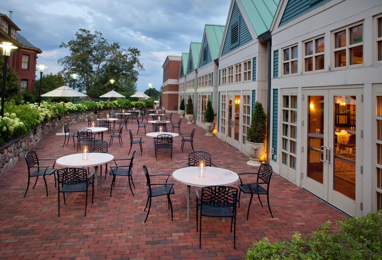 A red-brick outdoor dining area at Beechwood Hotel, with candlelit tables and parasols beside a greenery-lined wall