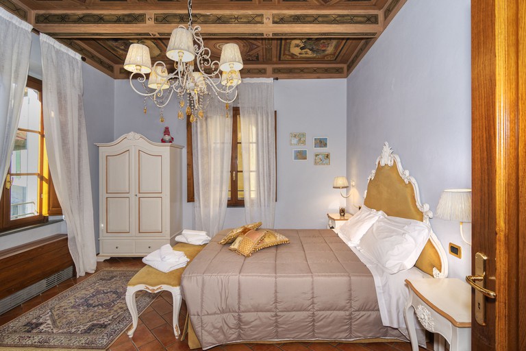 A bed, wardrobe, chandelier and wooden ceiling with frescoes in a guest room at Rinascimento Bed and Breakfast