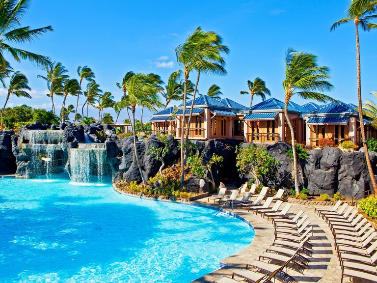 The palm tree fringed outdoor pool and sun-lounging terrace at Hilton Waikoloa Village.