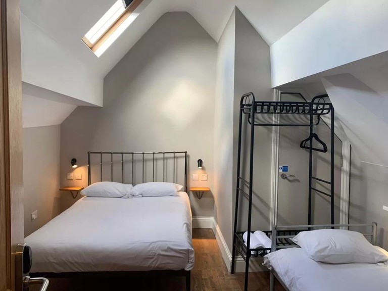 Two beds and a luggage rack with clothing rail in a guest room at the Riverhouse