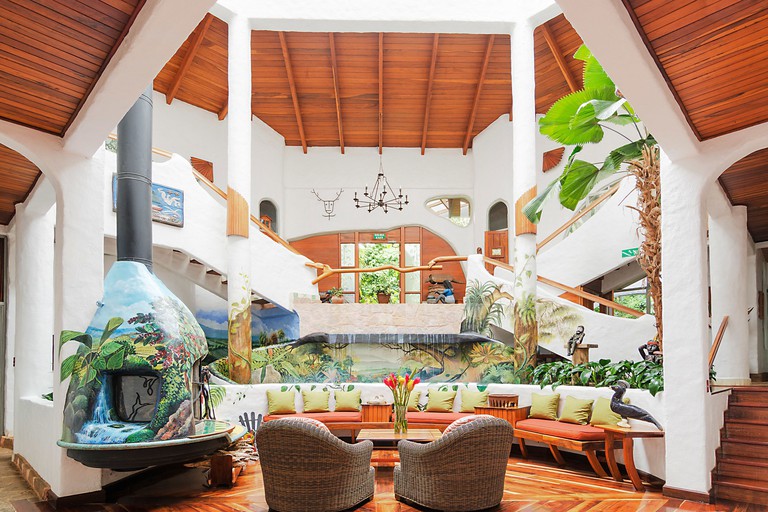 An airy sitting area at Finca Rosa Blanca Coffee Farm and Inn, with tropical murals, a water feature and wood ceilings