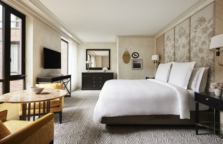 A bed and sitting area in a stylish hotel room at the Four Seasons Hotel Boston