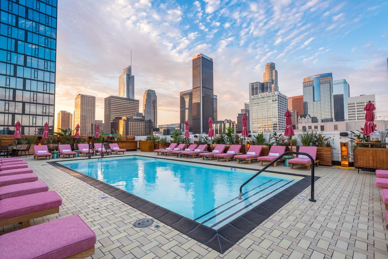 The rooftop pool area at Freehand Los Angeles with pink-cushioned lounge chairs and panoramic skyline views