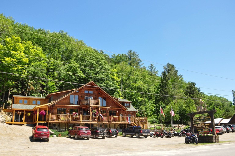 An outside view of the log-cabin-style Hawk’s Nest Lodge with trees behind it and parking in front