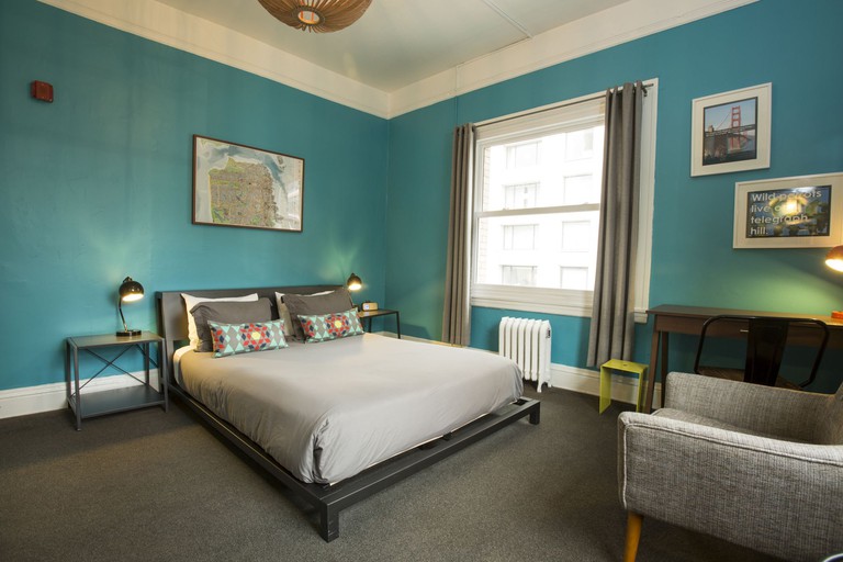 A double room at HI San Francisco Downtown has blue walls, grey furniture and city views