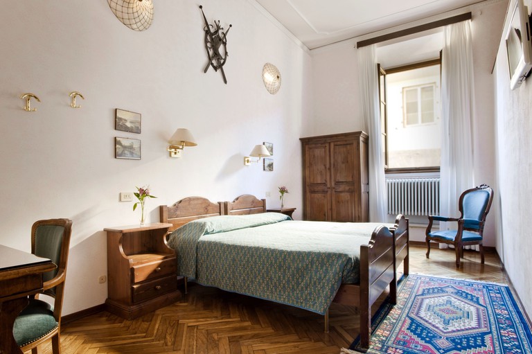 Traditional Florentine bedroom with antique furnishings, parquet floors and high ceilings at Hotel Alessandra, Florence