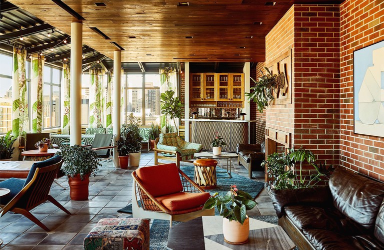 Contemporary lounge and bar area filled with mid-century furniture and pot plants at the Hotel Revival