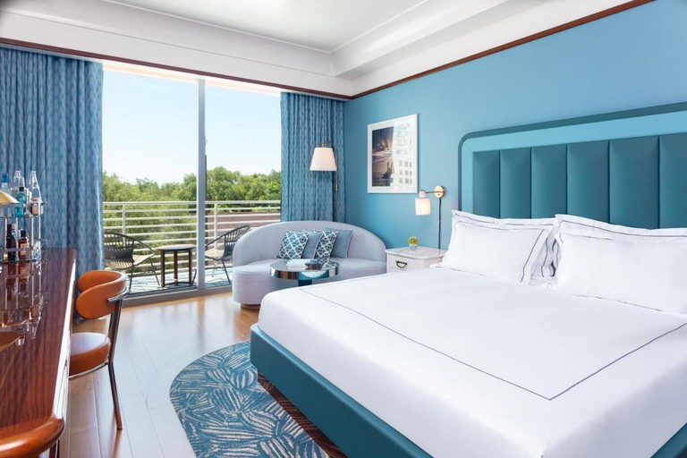 Retro chic king room in shades of aqua blue with polished wood floors and balcony at Mr. C Miami – Coconut Grove