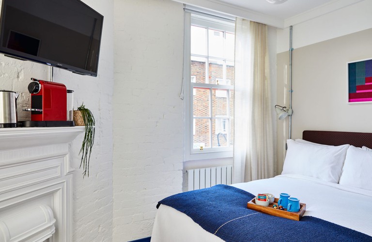 Double room at the Buxton has all-white design, a blue bed throw, a wall-mounted TV and a Nespresso coffee machine