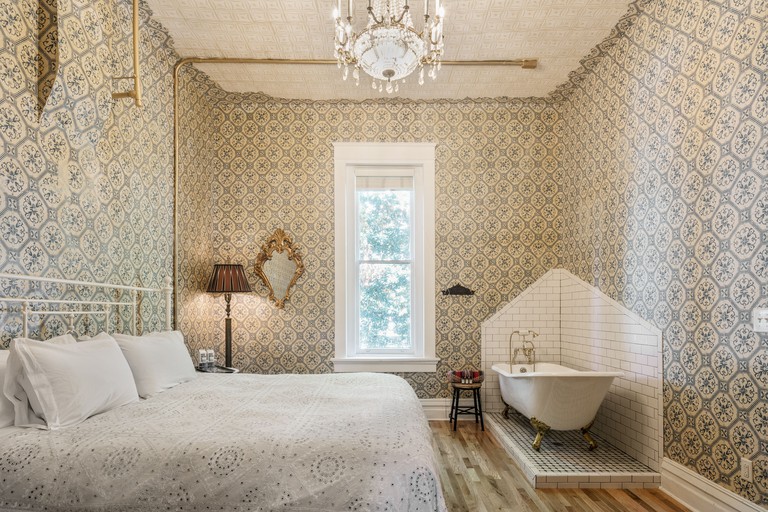 A double room at the Urban Cowboy features bold wallpaper, a standalone bath and antique decor