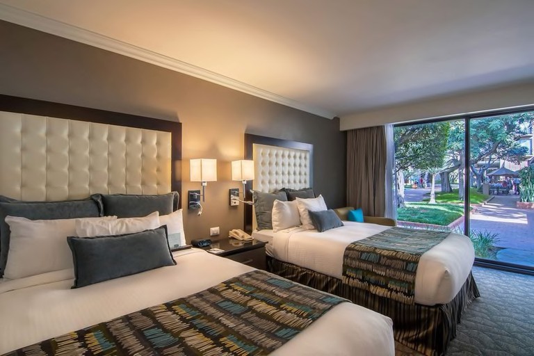 A double twin room with garden views at Hotel Lucerna Tijuana, with modern decor and mood lighting