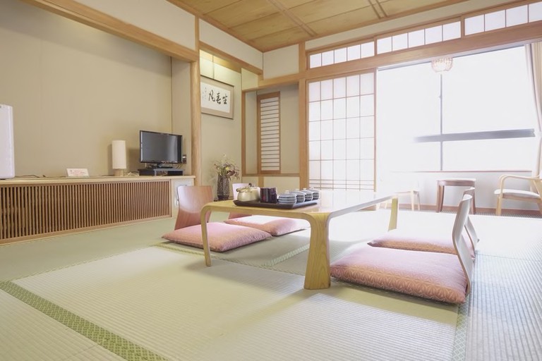 A room with a low table, a flatscreen TV and large windows at Kaneyoshi Ryokan