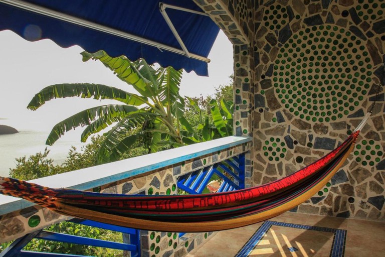 A colourful hammock hangs over a mosaic wall at Aleli Cottages