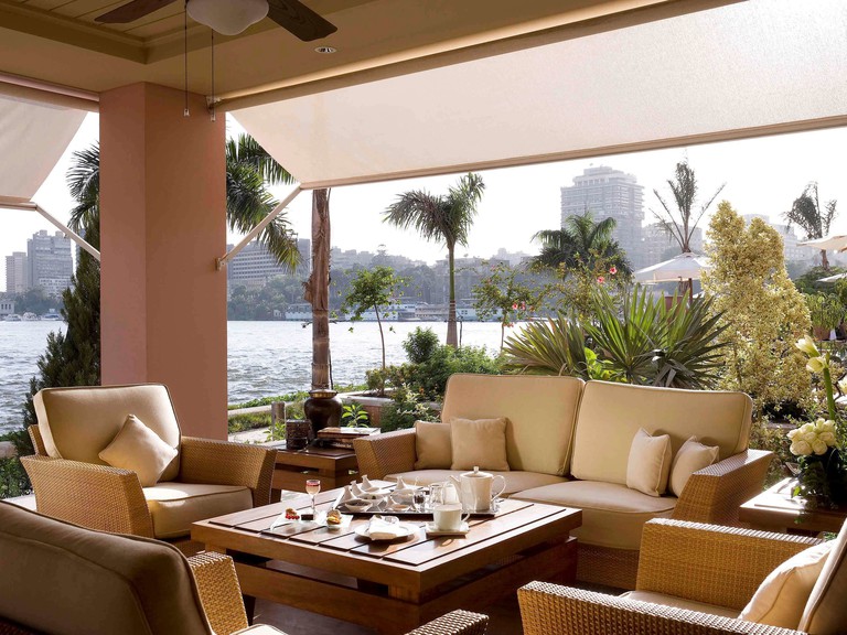 Tropical plants surround a outdoor seating area on the banks of the Nile at Sofitel Cairo Nile El Gezirah