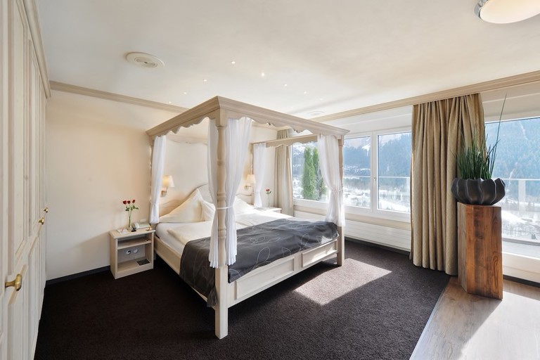King room with white four-poster bed and windows with broad views at Eiger Selfness Hotel – Zeit für mich, Grindelwald