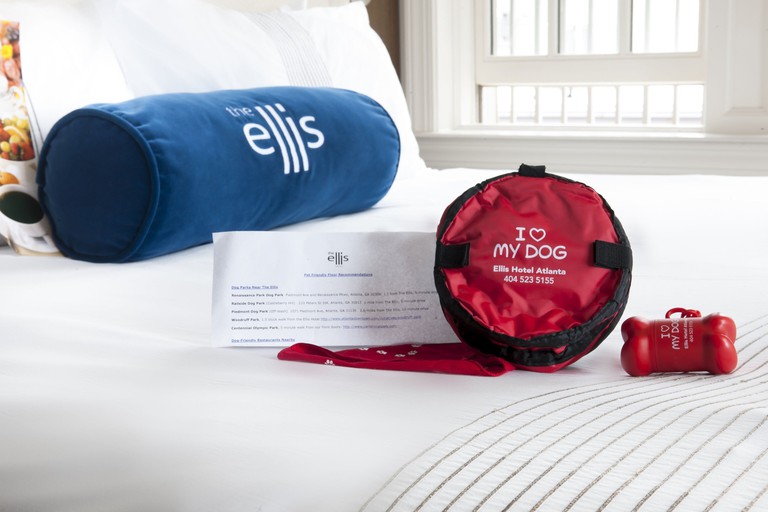 A bag reading "I Heart My Dog" on a white hotel double bed with an Ellis-branded pillow