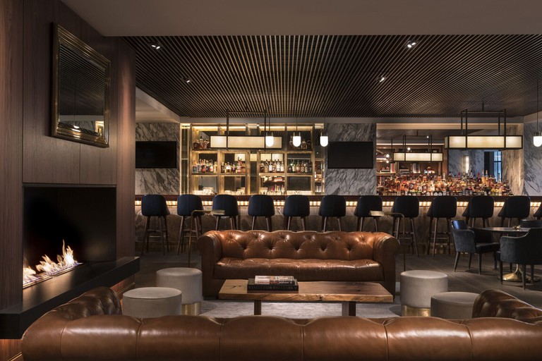 A bar in a hotel, with a fire place and two leather couches