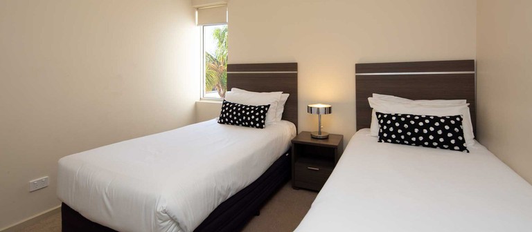 A simple bedroom with two beds at Hume Serviced Apartments