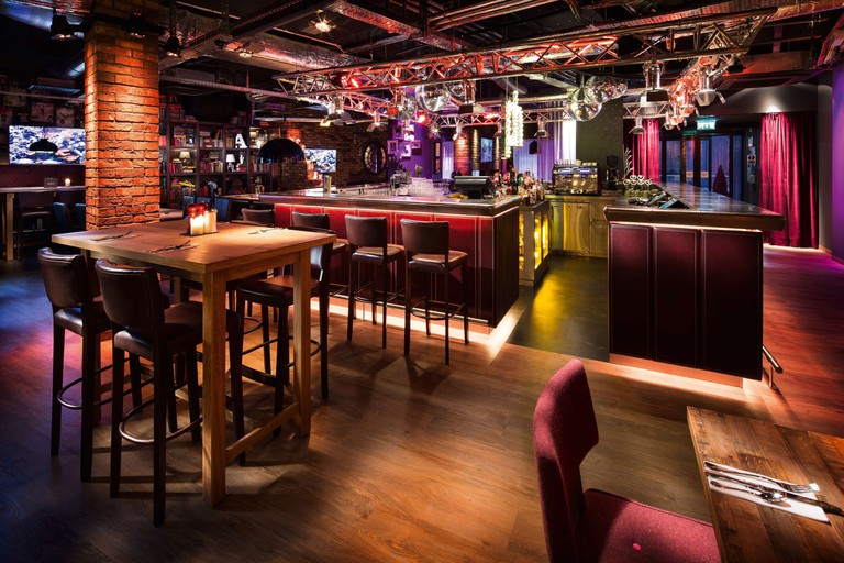 A stylish industrial-chic bar with dramatic mood lighting and wood floors at Penta Hotels Inverness