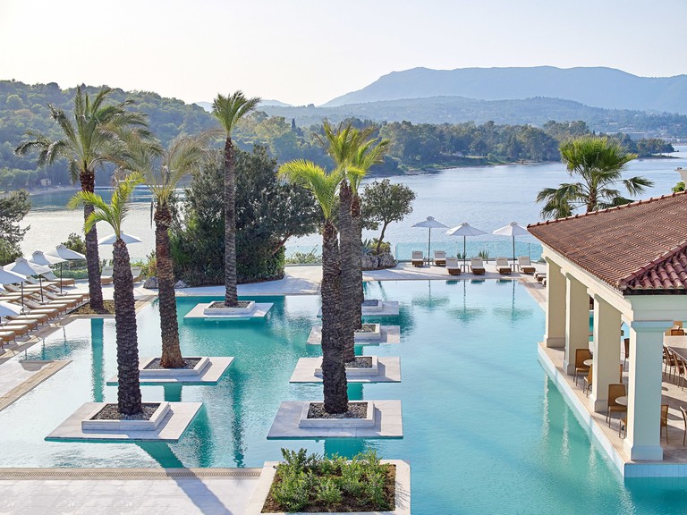 An outdoor pool at Grecotel Eva Palace with palm trees