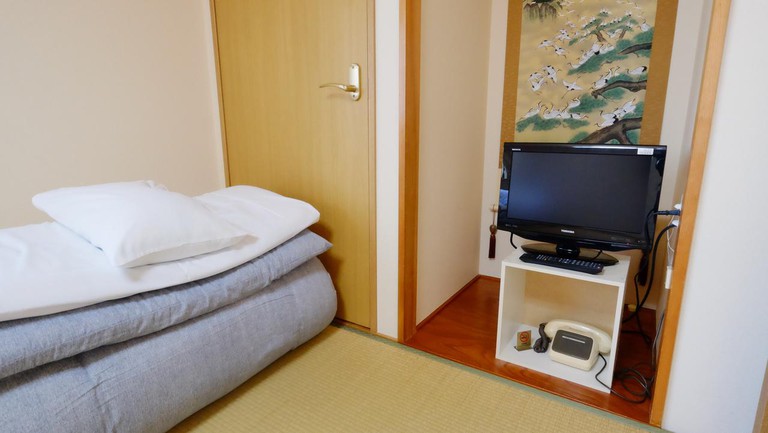 A small room with monitor, Japanese art and bedding at Sansui Ryokan