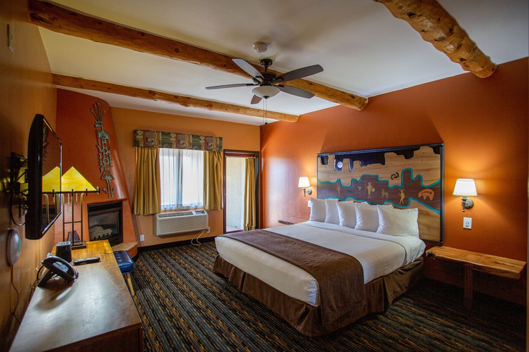 Double bedroom at Southwest Inn at Sedona with orange walls, patterned carpet and TV