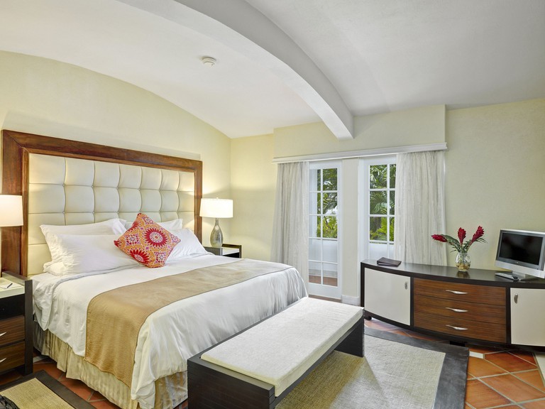 Bedroom at The House by Elegant Hotels 2, complete with curved ceiling, headboard, balcony and TV.