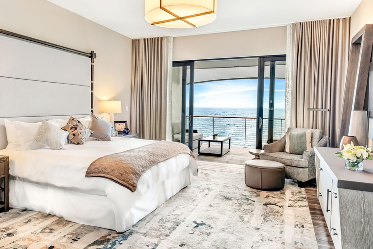 A double room at the Loren at Pink Beach is filled with coastal decor and features a seaview balcony