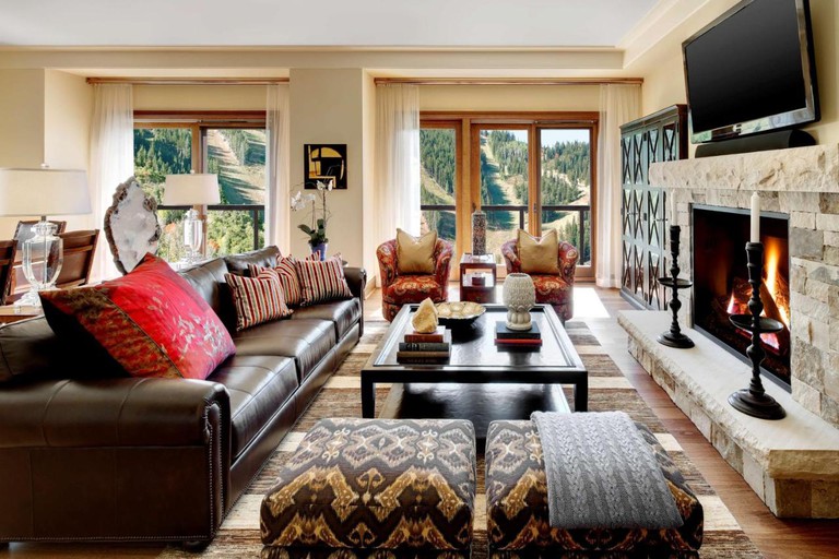 Luxurious living room with leather couch, stone fireplace and mountain views at the St. Regis Deer Valley, Utah