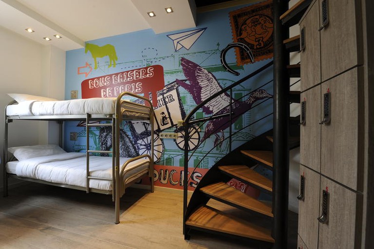 Bunk bed with white sheets against a wall with a mural and a curved spiral staircase with wooden steps at 3 Ducks.