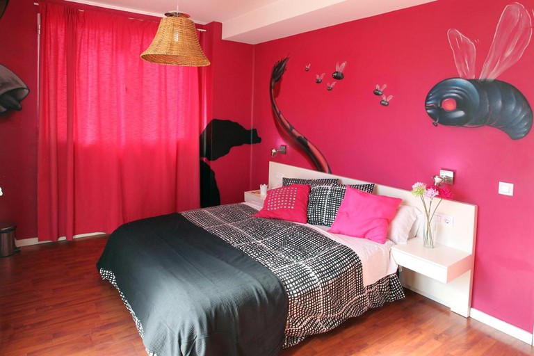 Bright pink room with flies painted on wall at Purple Nest Hostel Valencia