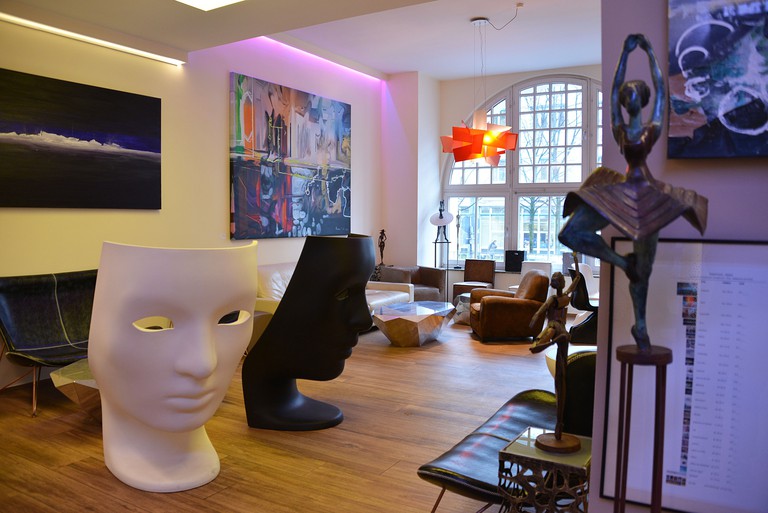Sculptures, artwork, figurines of dancers and seating in the lobby of Arthotel Munich