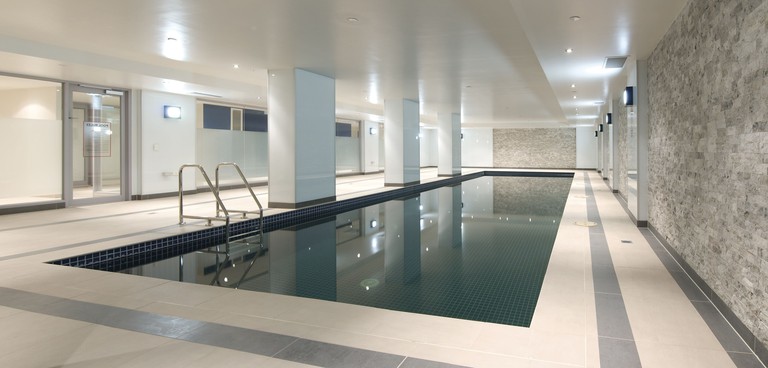 The indoor pool at Atlantis Hotel is long and sleek with artificial lighting and grey stone walls