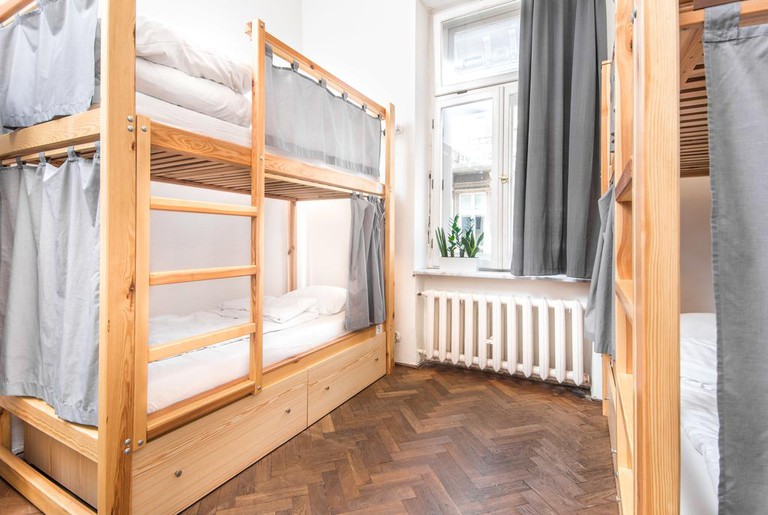 Two wooden bunk beds with curtains in a hostel dorm room at Bison Hostel in Krakow