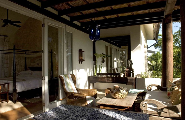 A sheltered outdoor seating area at Casa Colonial Beach & Spa, with a hanging light, a low coffee table, arm chairs and a rug