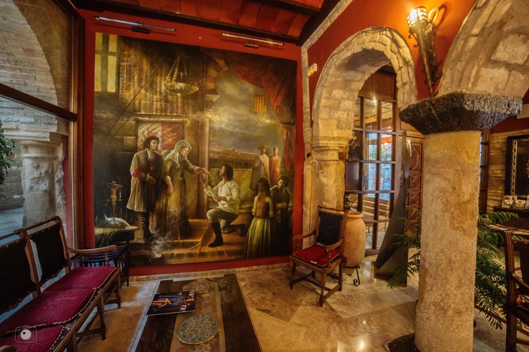 Large artwork in the lobby, with marble floors and stone arches, at Hacienda Posada de Vallina in Córdoba