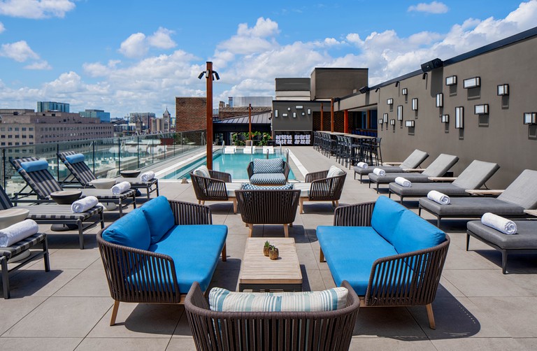 A rooftop pool, with couches in front of it and sun loungers on each side at Holston House Nashville, Unbound Collection by Hyatt