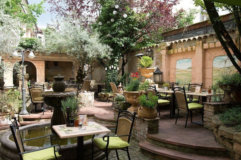 Tables, chairs, potted plants and trees in the courtyard at Hotel Gio