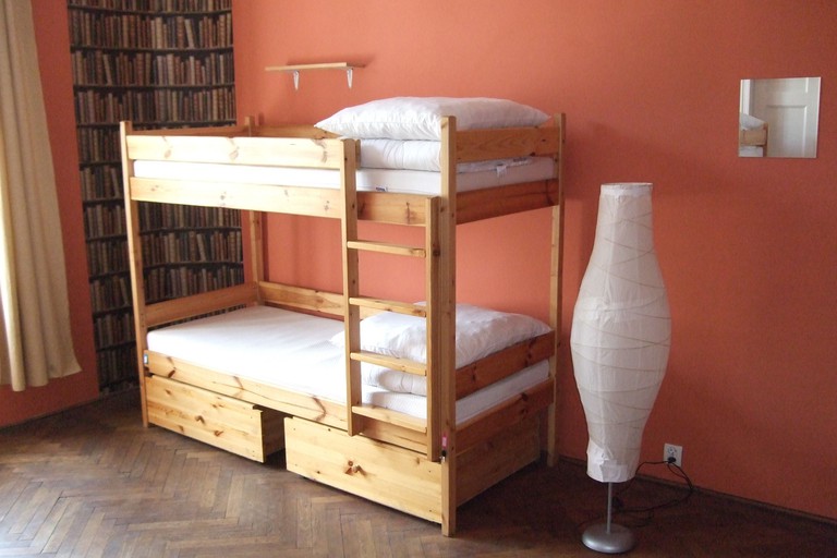 A wooden bunk bed and a floor lamp in a guest room at Old Walls Hostel in Krakow
