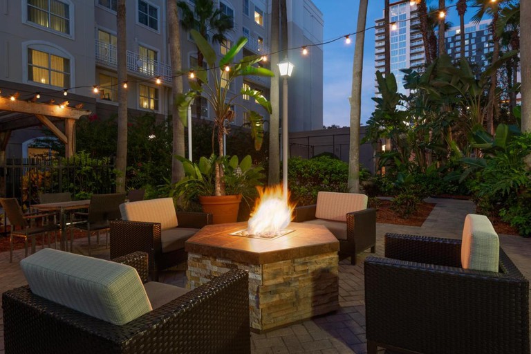 Cozy fire pit seating area with string lights and tropical foliage at Courtyard by Marriott Tampa Downtown