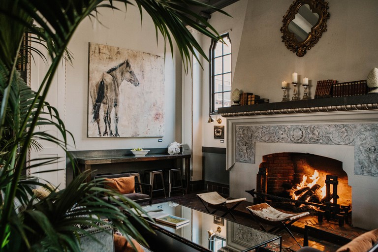 A cozy sitting area with a fireplace, books, candles, plants and a horse painting at Hotel Petaluma, Ascend Hotel Collection