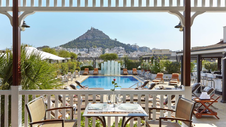 Rooftop pool at Hotel Grande Bretagne, surrounded by sunbeds and seating, with views of the Acropolis