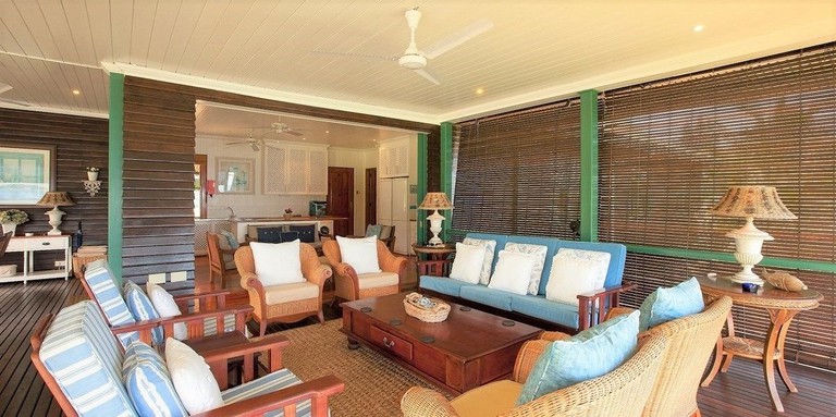 A seating area with a wooden table, armchairs and cushioned sofas at South Point Villas Cerf Island