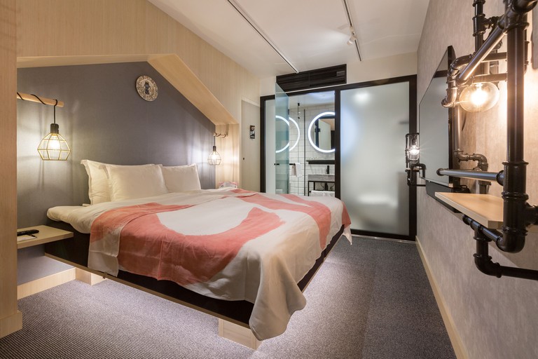 Ensuite bedroom at Hotel with Urban Deli, Stockholm, with a large double bed, wall-mounted TV and industrial-style finishings