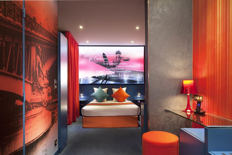 A hotel room with a bed and artwork with French phrases on the wall at Hotel Montmartre Mon Amour