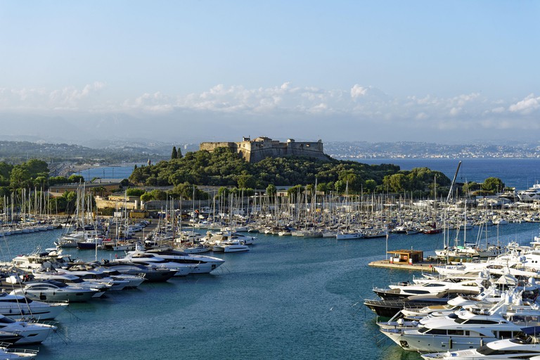 Fort Carré on top of a promontory in Antibes, with many yachts and sailboats in the marina in front of it