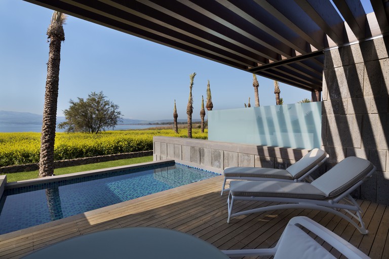 A terrace overlooking a rectangular pool at The Setai Sea of Galilee, with the ocean in the background