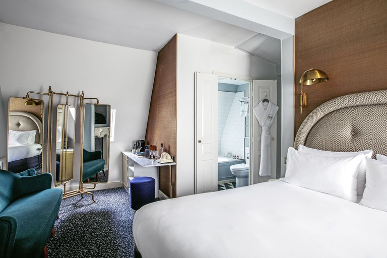 A bed, bathroom, chair, mirror and desk in a hotel room at Grand Pigalle Hôtel