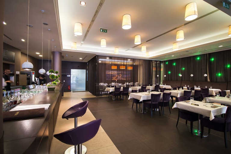 Large bar with purple furniture and dark tiled floor at Corso Hotel Pécs.
